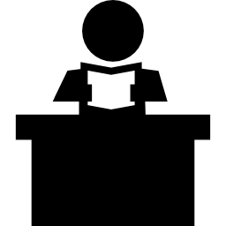 Teacher reading a book sitting behind his desk icon