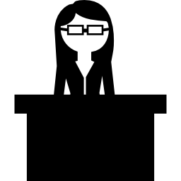Teacher with eyeglasses behind her desk icon